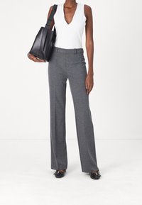 Šedé kalhoty se širokými nohavicemi s hladkým povrchem, kombinované s bílým topem s hlubokým výstřihem do V a černou koženou kabelkou, která má strukturovaný design.