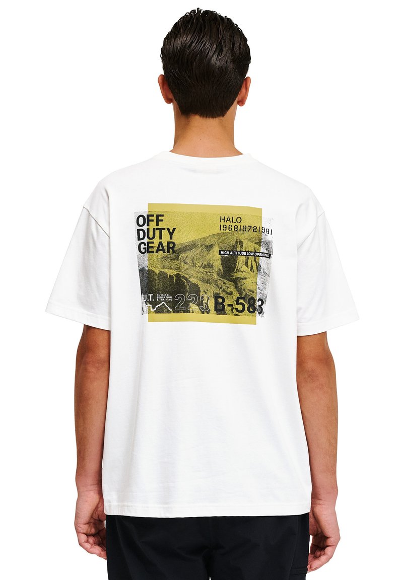 Hvid bomulds T-shirt med et grafisk print på ryggen, der inkluderer gul og sort tekst, herunder "OFF DUTY GEAR" og bjergmotiver.