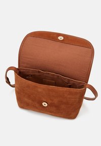 Brun suede taske med en blød tekstur, rund knaplukning og et enkelt håndtag. Indvendigt foret med et glat brunt stof.