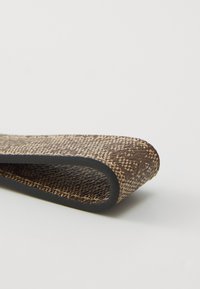 Sangle tissée marron texturée avec un bord en caoutchouc noir, présentant un motif et un dessous lisse, conçue pour une durabilité optimale.