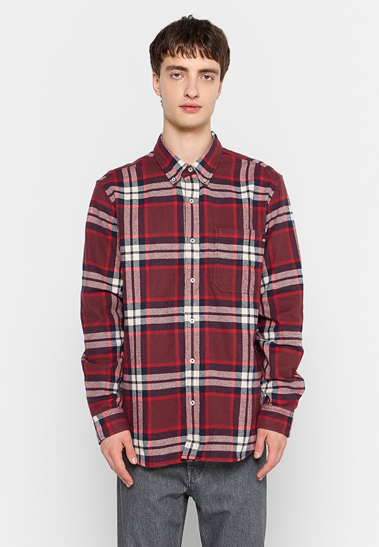 Camicia di flanella a quadri rossi e blu navy con colletto a button-down, maniche lunghe e taschino sul petto. Tessuto texturizzato con un classico motivo a scacchi.