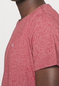 Červené tričko s krátkým rukávem z texturované tkaniny, s žebrovaným výstřihem a malým logem na prsou.