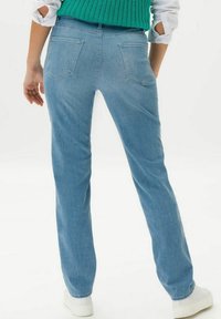 Ljusblå denimjeans med rak benform, som har två bakfickor och ett midjeband. Matchas med en grön stickad topp och vita sneakers.