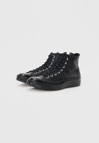 Czarne sneakersy typu high-top wykonane z gładkiej skóry, z okrągłym noskiem, metalowymi oczkami na sznurówki i teksturowaną gumową podeszwą.