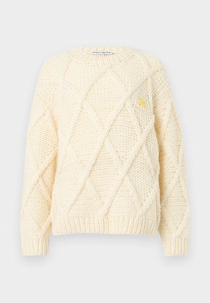 Suéter tejido color crema con patrón de rombos, cuello redondo, mangas largas y pequeño logo amarillo bordado en el lado izquierdo del pecho.