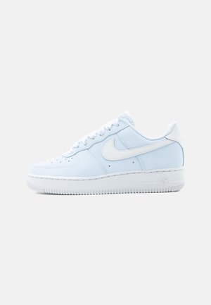 Biały niski sneaker Nike Air Force 1 z sznurowaniem i charakterystycznym logo Swoosh po boku na jednolitym tle.