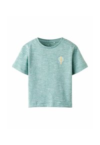 Camiseta corta de mangas en verde claro, con un patrón texturizado y un pequeño detalle bordado de un globo aerostático en el pecho.