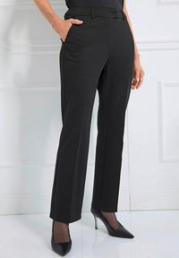 Zwarte op maat gemaakte broek met een recht gesneden ontwerp, voorzien van zijzakken en een gladde, gestructureerde stof. Gecombineerd met zwarte puntige hakken.