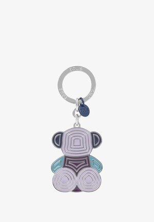 Llavero plateado con la palabra TOUS grabada, que sostiene un colgante geométrico en forma de oso en tonos morados, azules y rosas, además de una pequeña etiqueta azul marino.