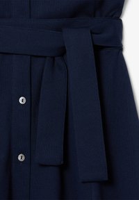 Abito blu navy con tessuto testurizzato, chiusura a bottoni e una cintura in tessuto coordinato annodata in vita.