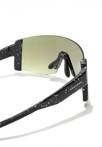 Juodi akiniai nuo saulės su blizgia, lašelių rašto apdaila. Jie turi didelį, išlenktą žaliai atspalvį turintį lęšį ir guminę nosies pagalvėlę patogumui.