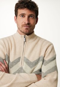 Beige zip-nek trui met zigzagpatronen in grijs en room. Gebreide textuur en geribde kraag. Ontspannen pasvorm, lange mouwen.