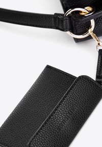Czarny portfel z teksturowanej skóry przymocowany do pasującego pasku torebki ze skóry w kolorze czarnym, z złotym metalowym pierścieniem i zapięciem.