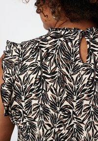 Bloemenpatroon top in zwart en beige met textuurstof, gerimpelde mouwen en een sleutelgatopening aan de achterkant.