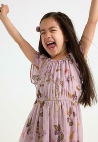 Lila blommig klänning med korta puffärmar, med flerfärgade blomster-mönster och en elastisk midja. Frisyr med ett lila håraccessoar.