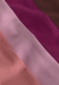 Close-up of ribbed fabric swatches in brown, dark pink, light pink, and peach colors arranged side by side.