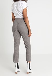 Grå rutiga byxor med skräddarsydd passform, hög midja och kort längd. Kombinerat med en lös vit t-shirt och vita ankelstövlar.