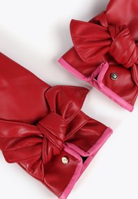 Röda läderhandskar med ett stort rosett-detalj vid handleden. Kantade i rosa, med knappstängning och slät textur.