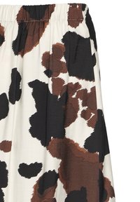 Tela de estampado de vaca en tonos marrón y negro con cintura fruncida, que presenta una textura suave. El diseño enfatiza formas abstractas y audaces sobre un fondo crema.