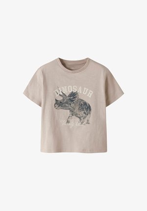 Beige lyhythihainen t-paita, jossa on triceratops-dinosauruksen kuva ja teksti "DINOSAUR Varsity Club" edessä.