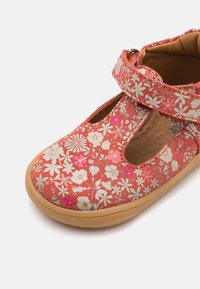 Červená botska s květinovým vzorem, se soft, strukturovaným svrškem, kulatou špičkou, bočními výřezy a páskem na suchý zip pro bezpečné uchycení.