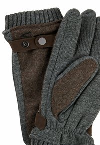 Grijze gebreide handschoenen met een bruine wolaccent, voorzien van een geribde manchetten en een drukknoopsluiting. Zachte textuur en contrasterende kleurelementen.