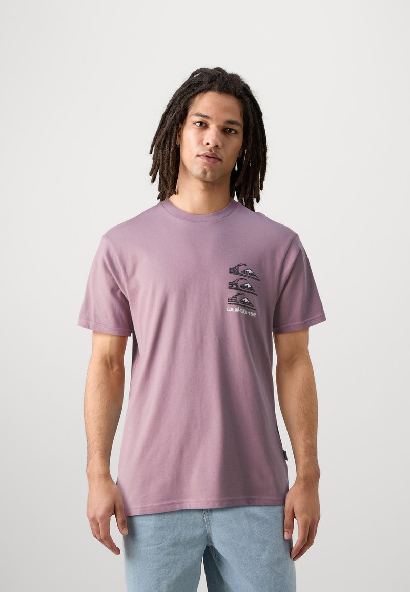Camiseta de algodón morada con un diseño gráfico de olas y montañas en el lado izquierdo del pecho. Mangas cortas, cuello redondo, corte relajado.
