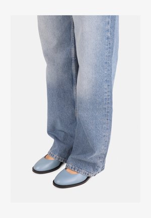 Sinised nahast madalad kingad ümmarguse varbaga ja lõikega disainiga, kombineeritud helesiniste laia säärega teksadega. Sile tekstuur ja minimalistlik stiil.