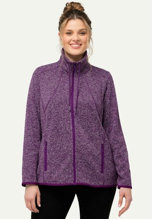 Violetti fleece-takki, jossa on vetoketjulliset taskut, korkea kaulus ja teksturoitu kuvio. Korostaa erottuvia violetteja vetoketju- ja helmaakkentteja.