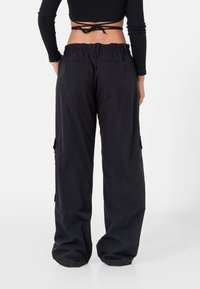 Zwarte cargobroek met een losse pasvorm, voorzien van een elastische tailleband, zijzakken en een gladde, lichtgewicht stof.