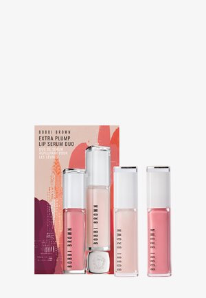 Bobbi Brown Extra Plump Lip Serum Duo innehåller tre glasbehållare med klara lock, i rosa och nude nyanser, på en färgglad mönstrad bakgrund.