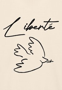 T-shirt beige con illustrazione in linea nera di una colomba che tiene un rametto d'ulivo, accompagnata dalla parola "Liberté" in una scrittura stilizzata.