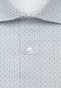 Gros plan d'une chemise bleu clair à motifs avec un petit motif floral et un bouton blanc visible près du col.