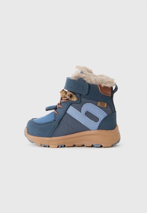 Bottine étanche bleue avec doublure en fausse fourrure beige, tissu texturé, semelle en caoutchouc et sangle ajustable. Comprend des accents en cuir marron.