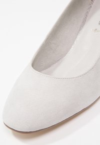 Ballerine en suède gris avec un bout arrondi, des lignes épurées et une doublure intérieure lisse. Construction légère avec des accents minimaux.