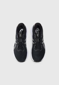 Chaussures de sport noires avec une tige en maille, semelle blanche et accents réfléchissants. Présentent une pointe ronde et six œillets pour un maintien sécurisé.