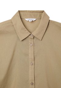 Camicia verde oliva con bottoni realizzata in tessuto morbido, caratterizzata da colletto classico, chiusura con sei bottoni e un'etichetta sul collo.