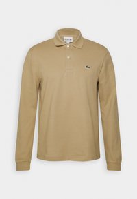 Khakifarbener langärmliger Poloshirt aus Baumwolle mit klassischem Kragen, Zwei-Knopf-Leiste und einem grünen, aufgestickten Logo auf der Brust.