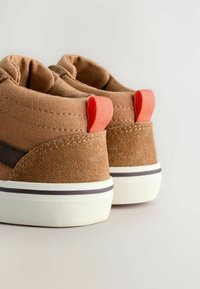 Brune lærred og ruskinds sneakers med hvide gummisåler, prydet med orange trækflapper og mørkebrune accenter.