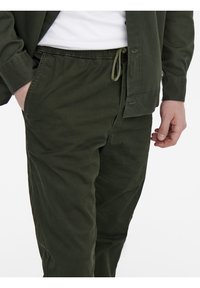 Olijf groene broeken met een elastische tailleband en verstelbaar koord, met een zachte, gladde textuur en een relaxte pasvorm.