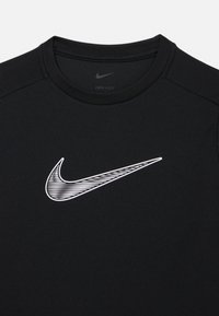 Čierne atletické tričko Dri-FIT s bielym logom Nike Swoosh a vzormi čiar. Hladká textúra, okrúhly výstrih a krátke rukávy.