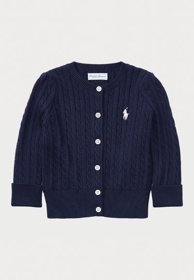 Marineblå kabelstrikket cardigan med hvite knapper, lange ermer, ribbestrikkede mansjetter og kant, og en liten hvit brodert logo på brystet.