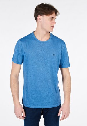 T-shirt blu a maniche corte con collo rotondo, realizzato in un tessuto texturizzato. Presenta un piccolo logo nero nella zona del petto sinistro.