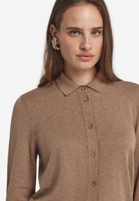 Brun stickad skjorta med krage, försedd med fem knappar fram och texturerad stickad tyg.