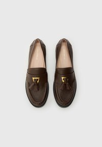 Brown leather loafers with a rounded toe, gold-tone hardware, and decorative tassels. Smooth texture with contrasting stitching details.
