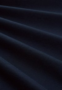 Bawełniana tkanina w kolorze granatowym o gładkiej fakturze, charakteryzująca się miękkimi fałdami i subtelnym połyskiem. Powierzchnia jest jednolita i pozbawiona widocznych wzorów.