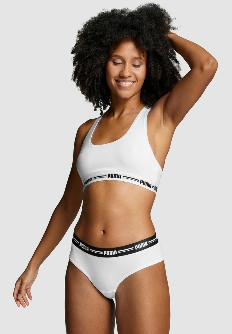 White sports bra and matching underwear with black "PUMA" logo accents. Stretchy material, simple design, and comfortable fit.