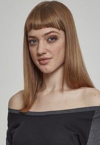 Off-the-shoulder svart topp med grå kant, med en avslappet passform. Gjevn tekstur, modell med rett, mellomlang blondt hår.