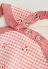 Rózsaszín-fehér kockás szövet kis piros cseresznye mintákkal, három ezüst patenttal egy rózsaszín bordázott szél mentén.