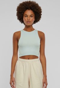 Light blue cropped tank top made of ribbed fabric, featuring a round neckline and sleeveless design, paired with beige elastic waistband pants.